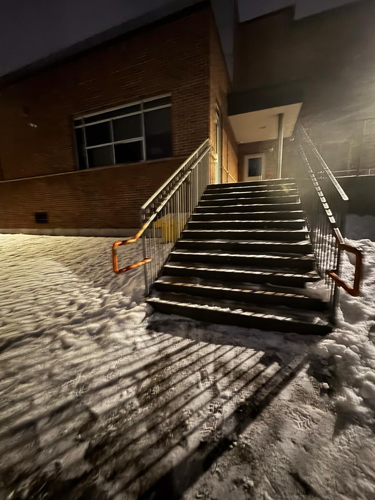 Snow-covered commercial entrance steps and handrails